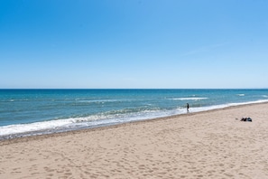 A beach with sand, a person walking, and a clear sky. - 3316 Casa Jacaranda (Marbella)