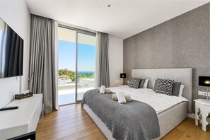 Ein modernes Schlafzimmer mit einem großen Bett, einem Fernseher und Blick ins Freie.
