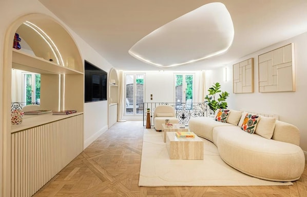 A modern living room with a sofa, coffee table, and a TV. - NESTLED IN THE VIBRANT & HISTORIC SAINT-GERMAIN WITH PRIVATE TERRACE – 3 BEDROOM (Paris)