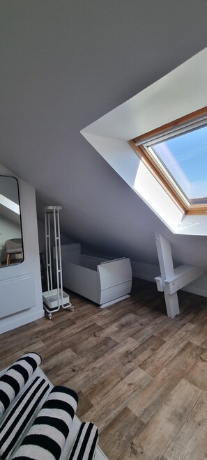 Un dormitori loft modern amb un fanal, un sofà blanc i un terra de fusta.