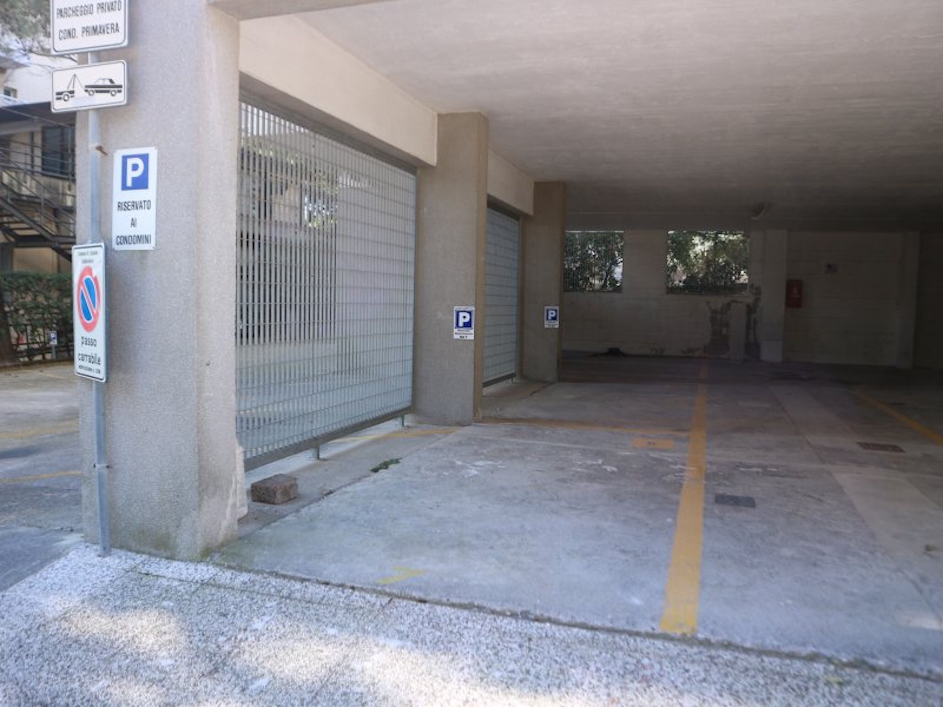 A parking garage with a gated entrance, a no parking sign, and a reserved parking sign.