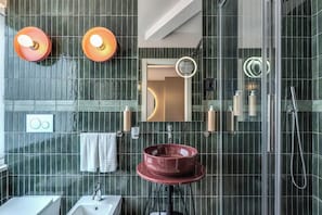 Une salle de bain moderne avec une douche à parois de verre, un lavabo rond et deux appliques murales.