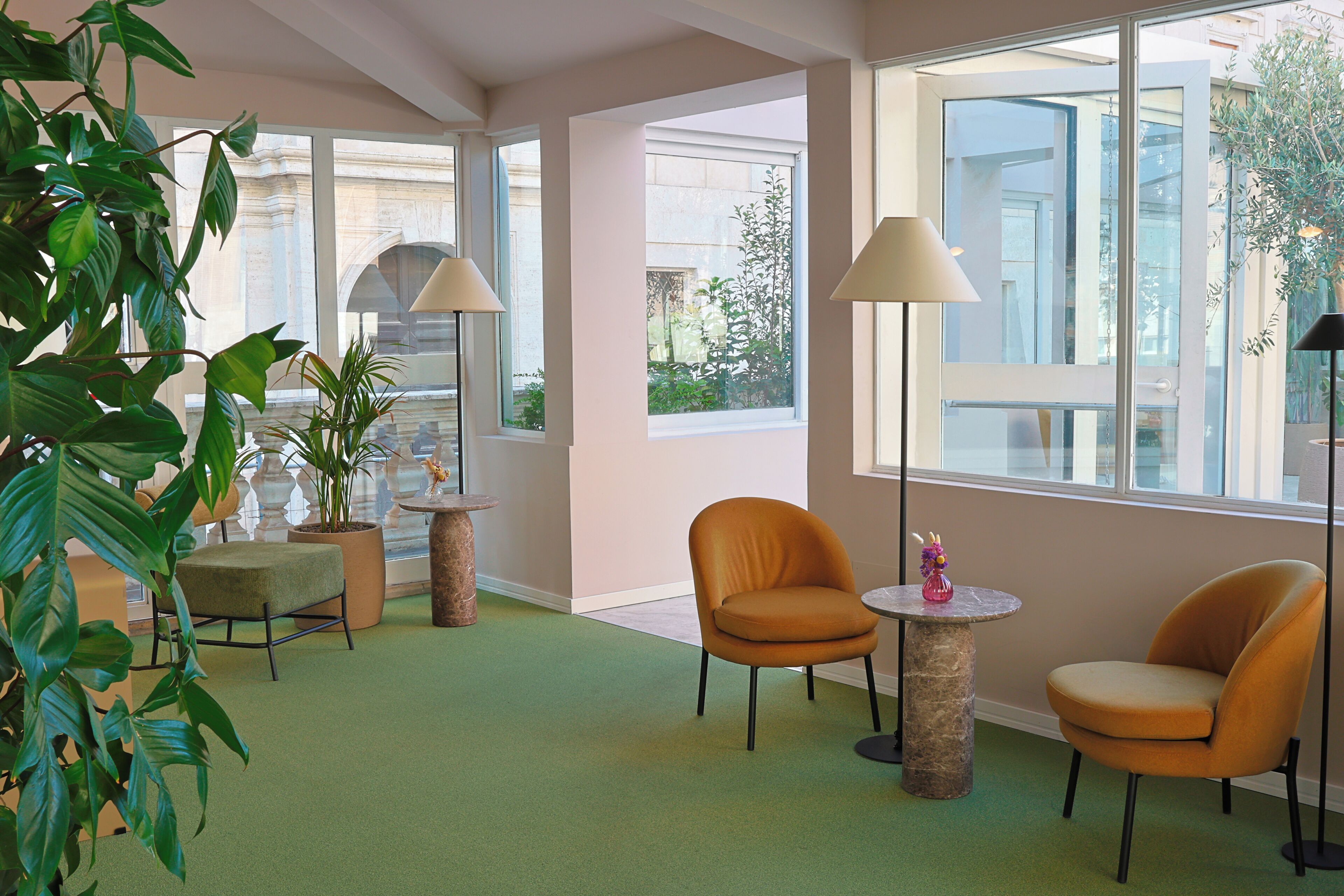 Una habitación con dos sillas anaranjadas, una mesita, una lámpara de pie y una planta en maceta.