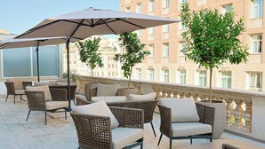 A terrace with wicker furniture, outdoor umbrellas, and potted plants. - Barberini 16 Boutique Hotel (Rome)