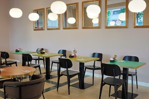 A dining area with multiple tables and chairs, a green and yellow color scheme, and large mirrors on the wall. - Barberini 16 Boutique Hotel (Rome)