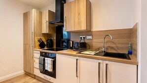 Eine moderne Küche mit Holzschränken, einer schwarzen Dunstabzugshaube, einem Einbauofen, einem Spülbecken und einem Geschirrspüler.