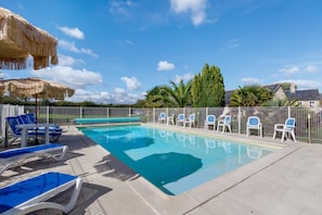 A swimming pool with lounge chairs and umbrellas, surrounded by a fence and greenery. - Puddle-duck Cottage – La Mare Chappey, children welcome, heated pool (Néhou)