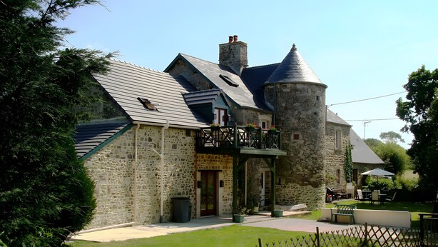 En byggnad i sten med ett litet torn, en balkong med räcken och en stenlagd innergård.