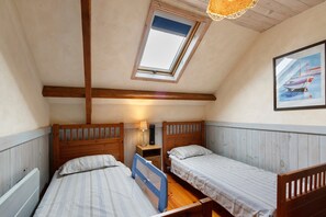 A room with two beds, a skylight, a painting, and a heater. - Puddle-duck Cottage – La Mare Chappey, children welcome, heated pool (Néhou)