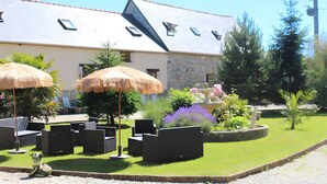 A building with a stone facade, a sloped roof, and multiple windows. - Gîte Grange – La Mare Chappey, child-friendly, heated pool (Néhou)