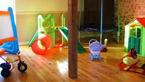 A playroom with a trampoline, play structures, and a small house. - Gîte Grange – La Mare Chappey, child-friendly, heated pool (Néhou)