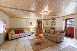 A cozy living room with two sofas, a coffee table, and a wooden ceiling. - Riverside Gîte – La Mare Chappey, Family-Friendly, Heated Pool (Néhou)
