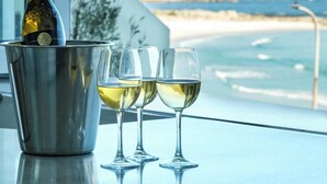 A bottle of wine in a bucket, three glasses, and a view of the ocean and mountains. - Camps Bay 6bed w Ocean Views and Pool Villa Sevara (Cape Town)