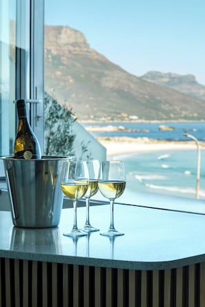 A bottle of wine in a bucket, three glasses, and a view of the ocean and mountains. - Camps Bay 6bed w Ocean Views and Pool Villa Sevara (Cape Town)