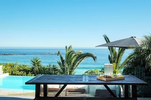 A wooden table with a drink tray, overlooking a pool and ocean view. - Camps Bay 6bed w Ocean Views and Pool Villa Sevara (Cape Town)