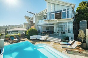 Een modern herenhuis met zwembad, buitenzitplaatsen en een balkon.