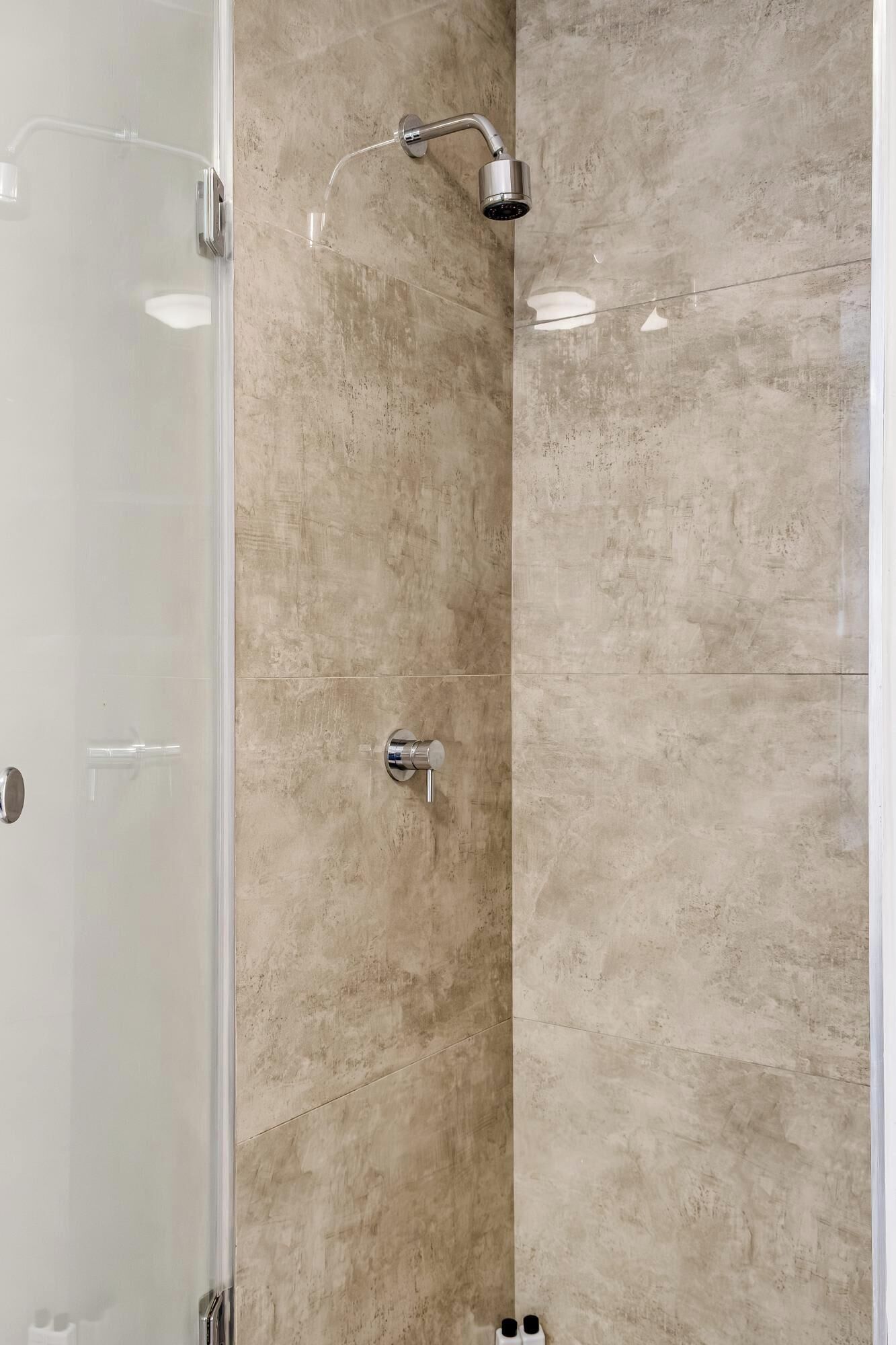A shower with a handheld showerhead and a wall-mounted control valve.