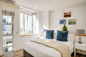Een slaapkamer met een bed, een nachtkastje, een lamp, een vaas en kunst aan de muur.