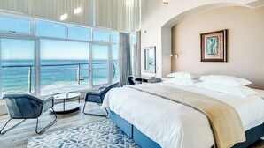 A bedroom with a large bed, a desk, a chair, and a view of the ocean. - Camps Bay 6bed w Ocean Views and Pool Villa Sevara (Cape Town)
