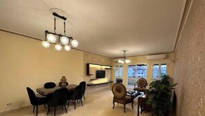 Uma área de refeições com mesa e cadeiras, uma TV fixada na parede e uma janela grande com vista.