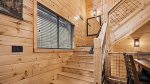 A wooden staircase leading to a second floor with a window with blinds, a wall-mounted light fixture, and a chair. - Minutes from Pigeon Forge - NEW 5 Bed/5Bath Rental - Slps 12 (Pigeon Forge)