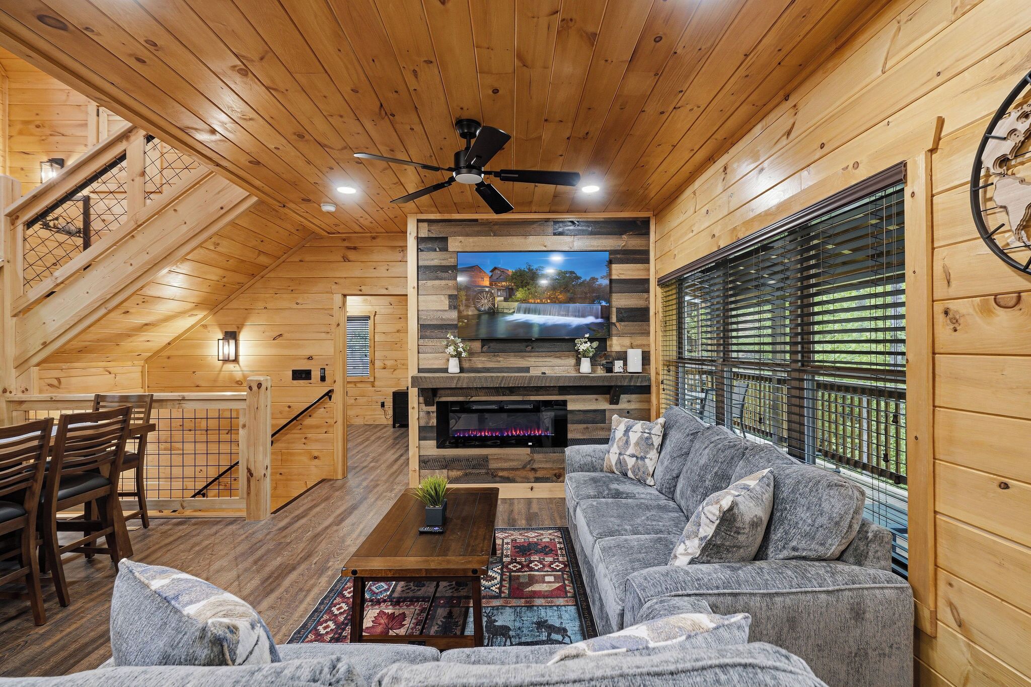 Een houten interieur met een televisie, bank en trap.