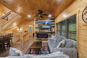 Een houten interieur met een televisie, bank en trap.