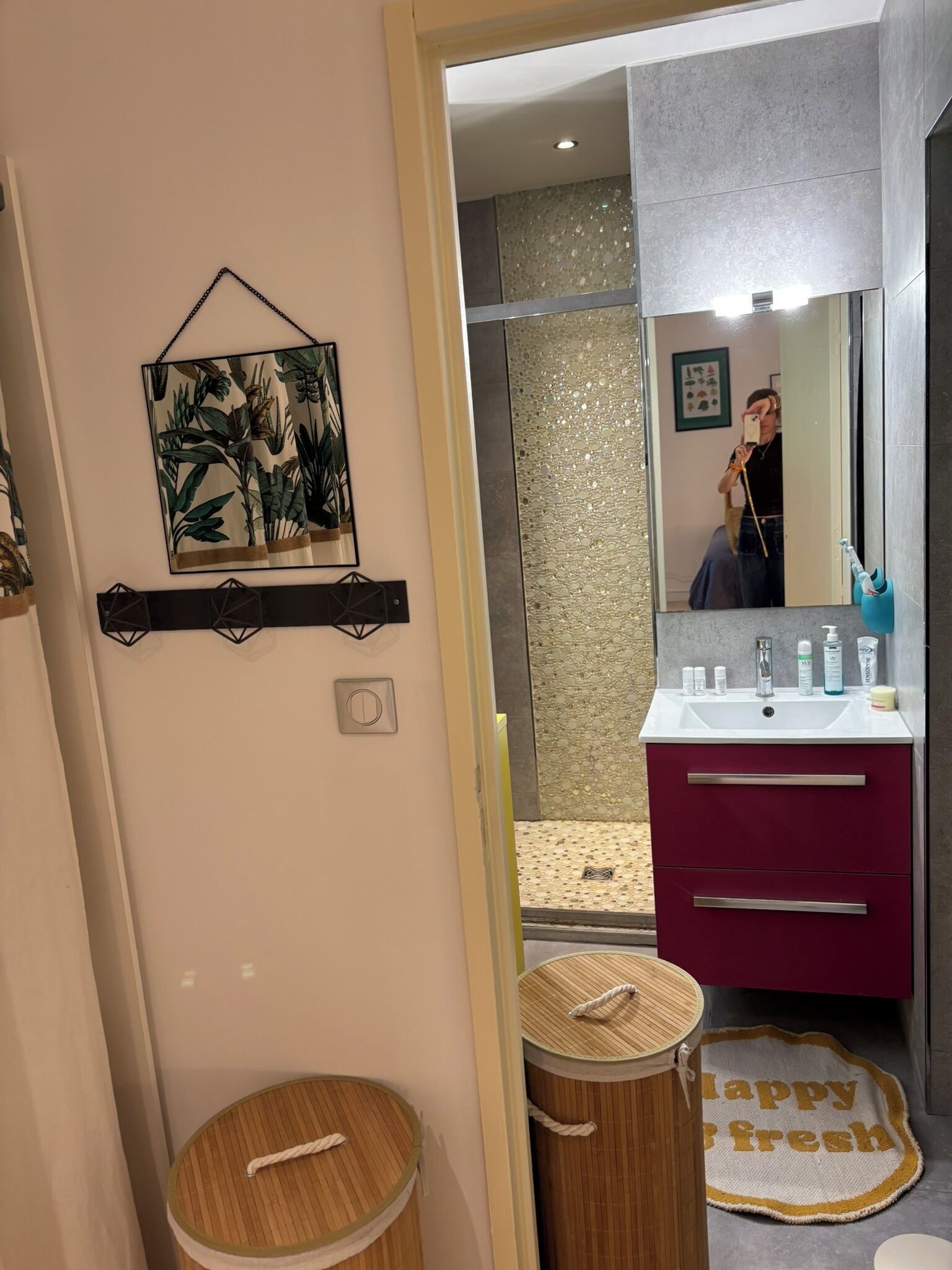 Et badeværelse med vaskebord, bruser, toilet og en dekorativ vægdekoration.
