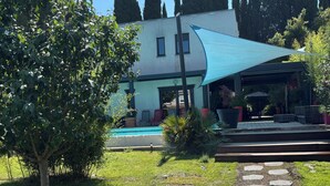 Un edificio moderno con piscina, rodeado de un césped cuidado y un sendero de piedra.
