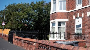 A red brick building with a bay window, a black metal fence, and a speed limit sign. - St Andrews By Guestz (Lytham Saint Annes)