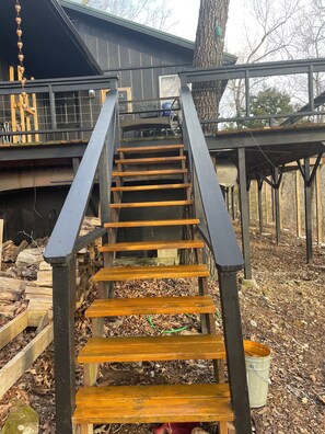 Eine Holztreppe mit Metallgeländern, die zu einem Deck führt.