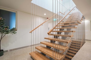 Un interior moderno con una escalera en espiral, una planta en maceta y una pared azul.