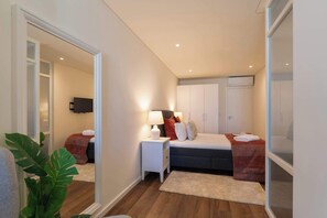 Un dormitorio con una cama, mesitas de noche, un televisor y un espejo grande.