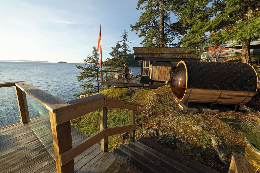 A wooden deck with a view of the water, a cabin with a hexagonal window, and a flag.