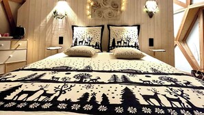 Un dormitorio con techo de madera geométrico, cama con ropa de cama estampada y lámparas de pared.