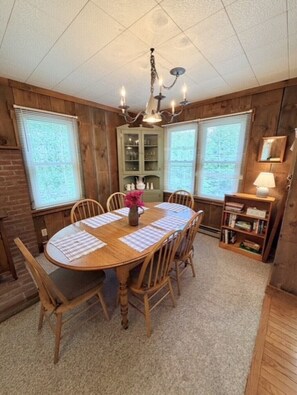 A dining room with a wooden table, chairs, a chandelier, and a cabinet with glass doors. - Barnside Bungalow in peaceful Laporte, PA. (Muncy Valley)
