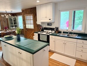 A kitchen with white cabinets, a green countertop, a stove, and a sink. - Barnside Bungalow in peaceful Laporte, PA. (Muncy Valley)