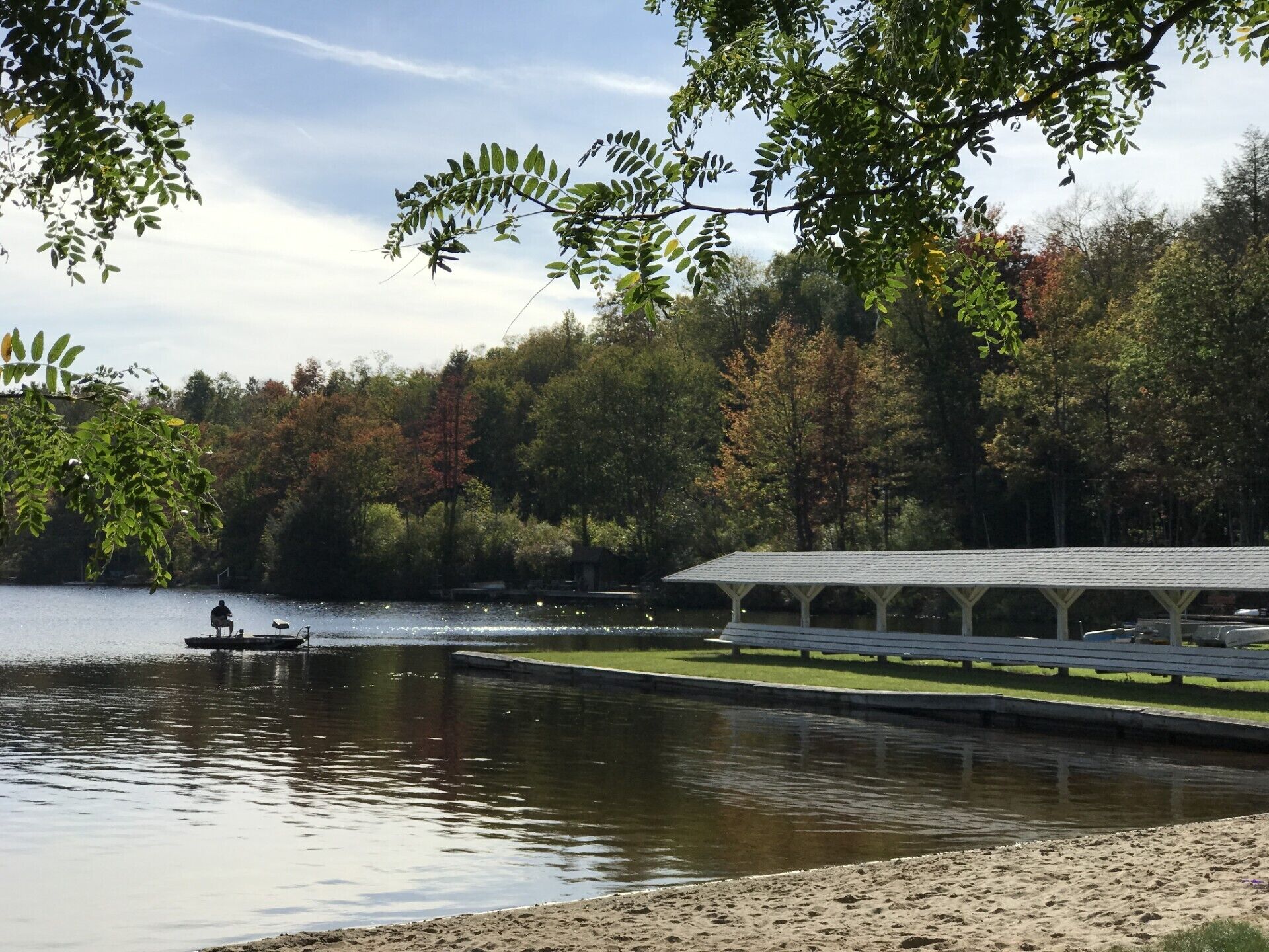 A lakeside view with a dock, a covered pavilion, and surrounding trees.