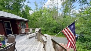 Eine Holzterrasse mit Gartenmöbeln, einer Ziegelwand und einer amerikanischen Flagge.