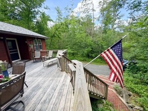 A wooden deck with outdoor furniture, a brick wall, and an American flag. - Barnside Bungalow in peaceful Laporte, PA. (Muncy Valley)