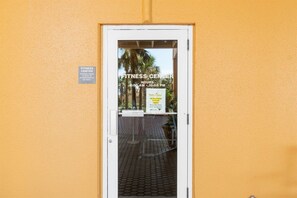 A door to a fitness center with a sign indicating hours of operation. - Luxury Beachfront 2BR Sleeps 8 Pool Amazing Views (Panama City Beach)