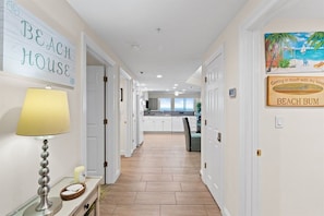 Een gang met een lamp, een bord waarop 'BEACH HOUSE' staat en een bord met een afbeelding van een strand.