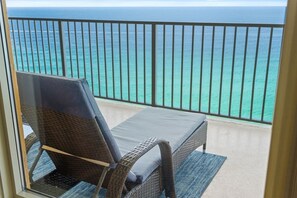 A balcony with a wicker chair and a view of the ocean. - Luxury Beachfront 2BR Sleeps 8 Pool Amazing Views (Panama City Beach)