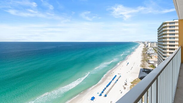 Blick auf einen Strand vom Balkon aus, mit blauem Himmel und Sandstrand.