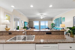 A kitchen with granite countertops, a double sink, and a ceiling fan. - Luxury Beachfront 2BR Sleeps 8 Pool Amazing Views (Panama City Beach)