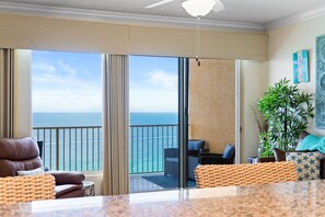 Une chambre avec vue sur l’océan, un balcon avec un fauteuil et un ventilateur de plafond.