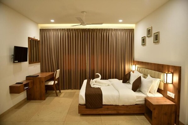 Una habitación de hotel con cama, escritorio, silla y televisión.