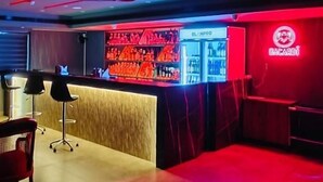 A bar area with a red neon sign, a counter with bottles, and a seating area with chairs. - GOLDEN STAR (Kollam)