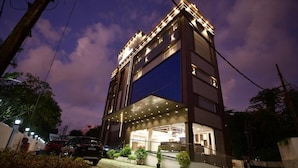 A modern building with a glass facade, a covered entrance, and a paved driveway. - GOLDEN STAR (Kollam)