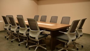 A conference room with a long table and eight office chairs. - GOLDEN STAR (Kollam)